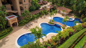 Un resort con varias piscinas rodeado de exuberante vegetación y palmeras.