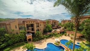 Un resort con varias edificaciones, una piscina central y vegetación circundante.