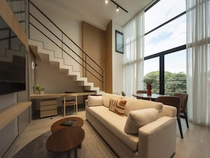 Ein modernes Wohnzimmer mit Treppe, einer Couch, einem Couchtisch und einem Essbereich.