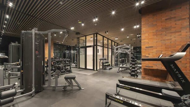 Een fitnessruimte met diverse trainingsapparaten, waaronder loopbanden en krachttoestellen.
