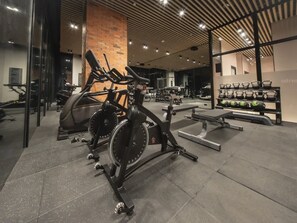 Ein Fitnessstudio mit stationären Fahrrädern, Kraftgeräten und einer Bank.