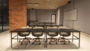 A conference room with a long table, multiple chairs, a brick pillar, and a large screen on the wall. - Modern 1br Apt great City View (Panamá)