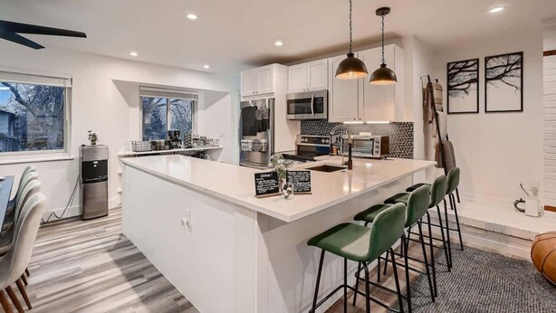 Una cocina moderna con una isla central, taburetes de bar e iluminación colgante.