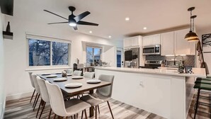 Una cocina moderna con armarios blancos, una isla central y un comedor con mesa y sillas.