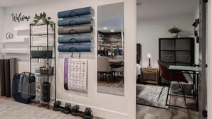 Un espacio habitable moderno con un zapatero fijado a la pared, un cartel de bienvenida y un área de comedor visible a través de un umbral abierto.