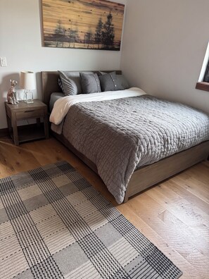 Ein Schlafzimmer mit Bett, Nachttisch, Lampe und einem Bild an der Wand.