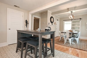 A dining area with a dark wooden table and matching chairs, a white door, and a patterned rug. - The Bulldog Farmhouse - 100+ year old home (Athens)