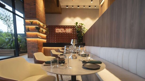 A modern restaurant with a round table set for dining, cushioned seating, and a wooden accent wall with a neon sign. - Cosmo 1br Apt near to coasts (Panamá)
