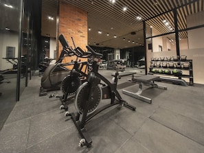 Un gimnasio con bicicletas estáticas, máquinas de pesas y un banco.