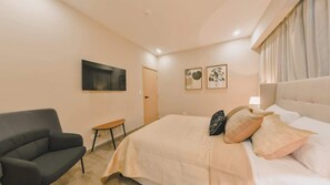 Ein Schlafzimmer mit Bett, einem Sessel, einem kleinen Tisch und Bildern an den Wänden.