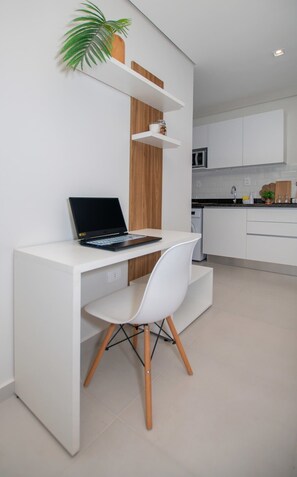 Eine moderne Küche mit weißen Schränken, einer integrierten Mikrowelle und einer Arbeitsplatte mit einer Kaffeemaschine.