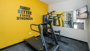 Een sportschool met een loopband, krachttoestellen en een motiverende quote op de muur.