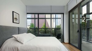 Et moderne soveværelse med en stor seng, en skydedør til en balkon og et billede i ramme på væggen.