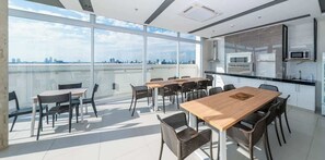 A modern conference room with large windows, a city view, and a kitchenette. - Sophisticated 1BR Apt, City Views & Great Location (Asunción)