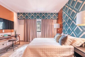A hotel room with a bed, a desk, a chair, a TV, and a patterned wall. - Santo Domingo Gem Modern Apartment with Amenities! (Santo Domingo)