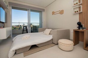 Quarto moderno com uma cama, um sofá, uma mesinha e uma televisão.