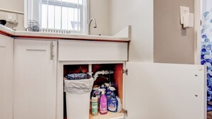 Ein Badezimmer mit einem weißen Waschbecken, einem Fenster darüber und einem Schrank darunter.