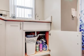 Ein Badezimmer mit einem weißen Waschbecken, einem Fenster darüber und einem Schrank darunter.