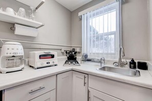 A kitchen with a coffee maker, toaster, and sink. - Downtown Olde Town Arvada- Across from light rail (Arvada)