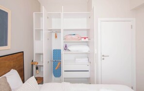 A bedroom with a bed, a white wardrobe with shelves, a door, and a wall-mounted light fixture. - Stylish 1BR King bed Pool, Gym, BBQ Prime Area (Asunción)