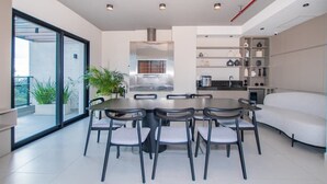 Una cocina moderna con campana de acero inoxidable, una mesa de comedor con sillas y horno empotrado.