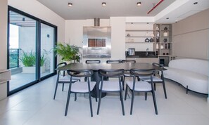 A modern kitchen with a stainless steel range hood, a dining table with chairs, and a built-in oven. - Stylish 1BR King bed Pool, Gym, BBQ Prime Area (Asunción)