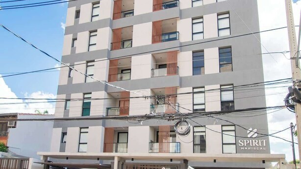 Un edificio de varios pisos con un diseño moderno, que presenta balcones con listones de madera, un garaje a nivel de calle y un cartel visible de 'SPIRIT MARISEAL'.