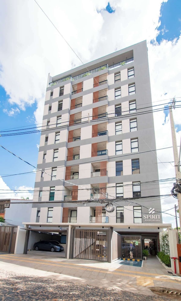 A multi-story building with a modern design, featuring balconies with wooden slats, a garage at the ground level, and a visible sign for 'SPIRIT MARISEAL'.