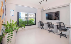 A modern office space with a large window, a flat-screen TV, and several office chairs.
