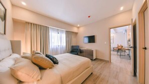 Ein modernes Hotelzimmer mit einem großen Bett, einem Schreibtisch und einem Fernseher.