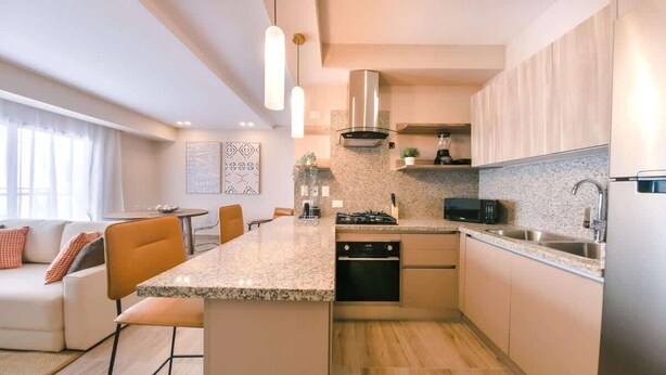 A modern kitchen with a central island, built-in appliances, and a dining area with a sofa and chairs. - Flat in Regatta Ii with breakfast included 304 (Santo Domingo)