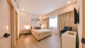 A hotel room with a bed, bedside tables, a desk, a chair, a TV, and curtains. - Flat in Regatta Ii with breakfast included 304 (Santo Domingo)