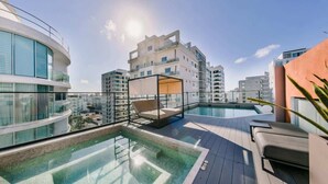 A rooftop pool area with a glass balustrade, lounge chairs, and a view of surrounding buildings. - Flat in Regatta Ii with breakfast included 304 (Santo Domingo)