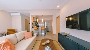 A modern living room with a sofa, coffee table, and a flat-screen TV. - Flat in Regatta Ii with breakfast included 304 (Santo Domingo)