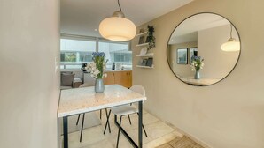 A modern kitchen with a dining area, a round mirror, and a vase with flowers. - Modern King Studio in Central Roma Norte (Ciudad de México)