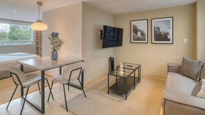 A modern living room with a sofa, a dining table with chairs, a TV mounted on the wall, and framed pictures. - Modern King Studio in Central Roma Norte (Ciudad de México)