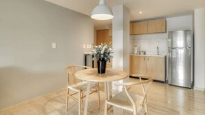 A modern kitchen with wooden cabinets, a stainless steel refrigerator, and a round dining table with chairs. - Modern King Studio in Central Roma Norte (Ciudad de México)