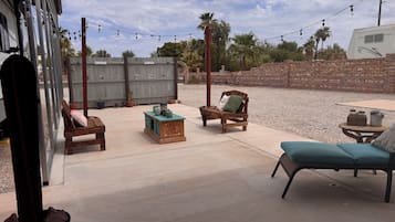 An outdoor patio area with a wooden bench, a small table, and a lounge chair.