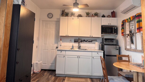A compact kitchen with white cabinets, a microwave, an oven, and a ceiling fan. - A GREAT PRICE! FOR A COZY CASITA, SECURED ON A LARGE PRIVATE LOT ALL TO YOURSELF (Yuma)