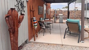 A covered patio area with a table and chairs, a barbecue grill, and decorative cacti. - A GREAT PRICE! FOR A COZY CASITA, SECURED ON A LARGE PRIVATE LOT ALL TO YOURSELF (Yuma)