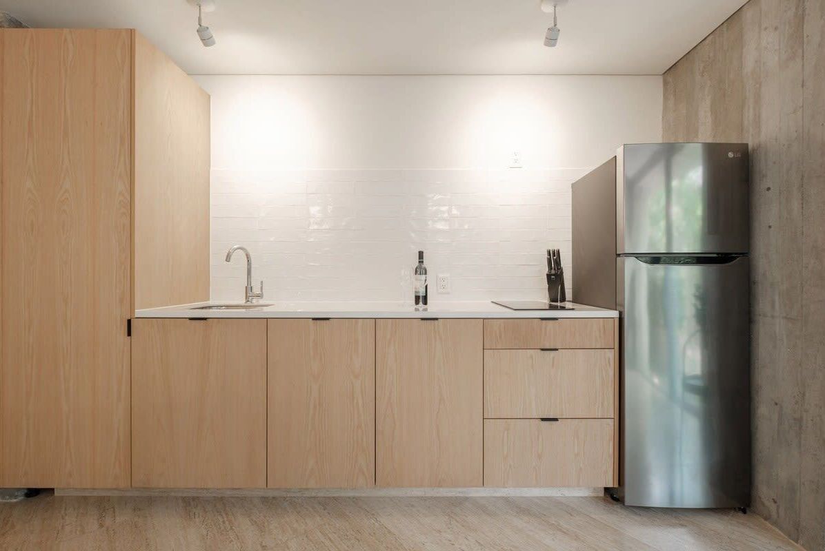 A modern kitchen with wooden cabinets, a stainless steel refrigerator, and a white tiled backsplash.