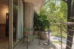 A balcony with a chair, a small table, and potted plants. - Modern Loft with Balcony & View of Parque Mexico (Ciudad de México)