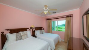 Une chambre d’hôtel avec deux lits, un ventilateur de plafond, une fenêtre avec des rideaux et une vue sur un terrain de golf.