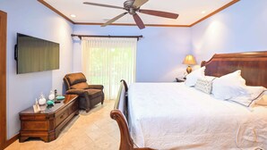 A bedroom with a bed, a chair, a nightstand, a TV, and a ceiling fan. - Veranda 1H -  3 bdr 3 bath Family (Playa Herradura)