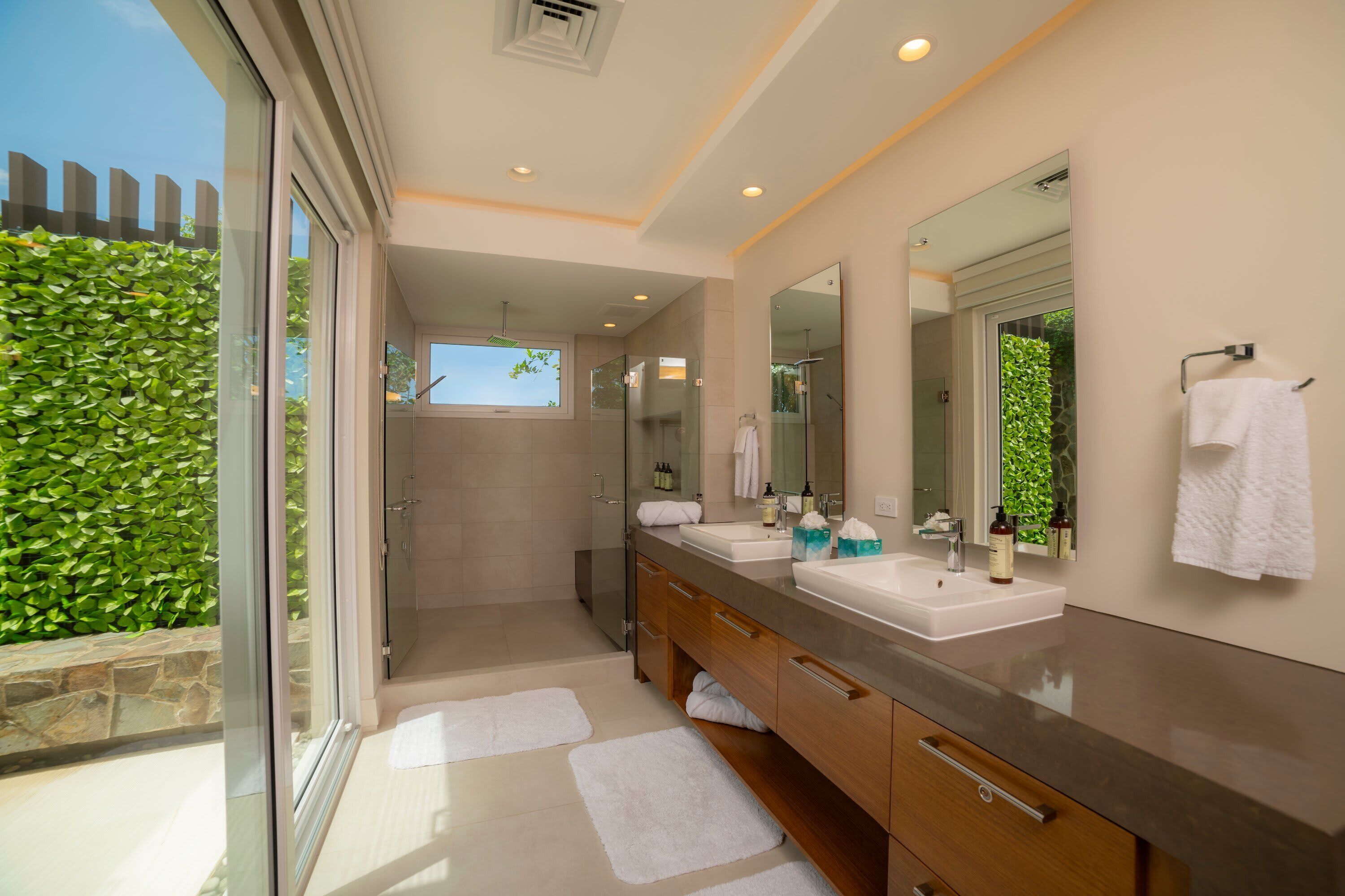 A modern bathroom with a glass shower enclosure, dual sinks, and a large mirror.