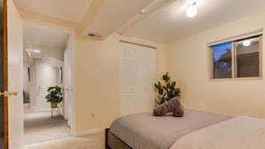 Un dormitorio con cama, ventana, puerta y un pasillo que conduce a otra habitación.