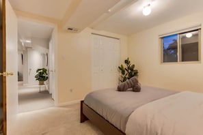 Ein Schlafzimmer mit einem Bett, einem Fenster, einer Tür und einem Flur, der in einen weiteren Raum führt.