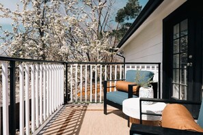 A balcony with a white fence, a blue chair, a brown cushion, and a small table with a plant. - House of Noir Elan Stunning 6BR Designer Retreat (Arvada)