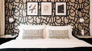 A bed with two pillows, a wall with a geometric pattern, and three framed artworks above the bed. - House of Noir Elan Stunning 6BR Designer Retreat (Arvada)