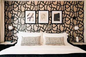 A bed with two pillows, a wall with a geometric pattern, and three framed artworks above the bed. - House of Noir Elan Stunning 6BR Designer Retreat (Arvada)